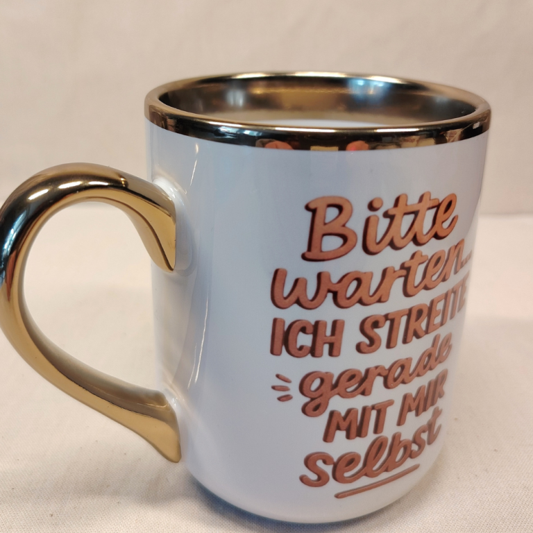 Tasse mit goldfarbigem Rand und dem Text: "Bitte warten, ich streite gerade mit mir selbst."