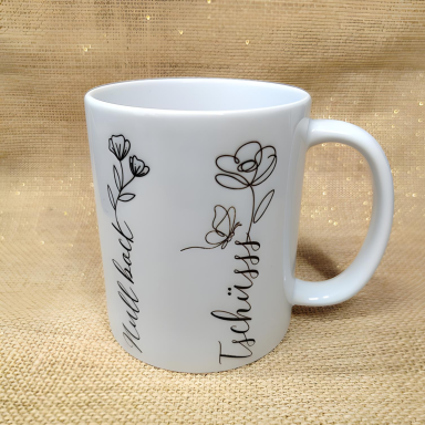 Weißer Becher mit floralem Muster und den Aufschriften "Will back" und "Tschüss".